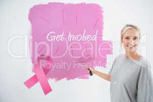 Composite image of happy young woman painting her wall pink