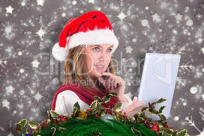 Composite image of festive blonde looking at tablet pc