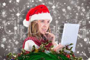 Composite image of festive blonde looking at tablet pc