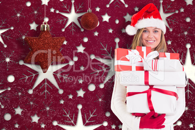 Composite image of festive blonde holding pile of gifts