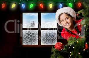 Composite image of festive girl looking from behind christmas tr