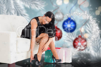 Composite image of woman sitting with shopping bags