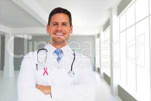 Composite image of handsome doctor with arms crossed