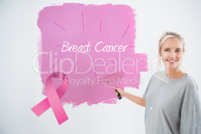 Composite image of happy young woman painting her wall pink