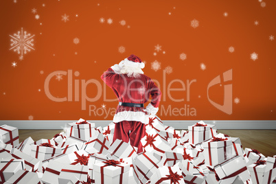 Composite image of santa standing on pile of gifts