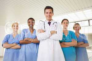 Composite image of smiling doctor and nurses with arms crossed