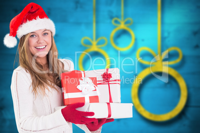 Composite image of festive blonde holding pile of gifts