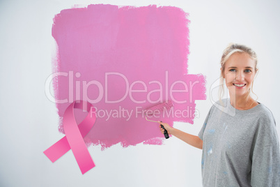 Composite image of happy young woman painting her wall pink