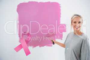 Composite image of happy young woman painting her wall pink