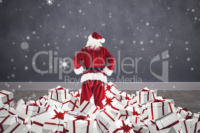 Composite image of santa standing on pile of gifts