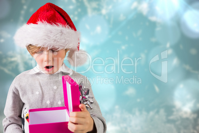 Composite image of festive boy holding a gift