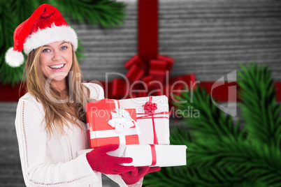 Composite image of festive blonde holding pile of gifts