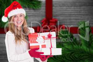 Composite image of festive blonde holding pile of gifts