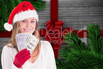 Composite image of festive blonde showing fan of dollars