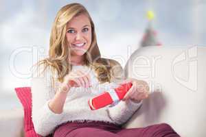 Composite image of pretty blonde opening a gift