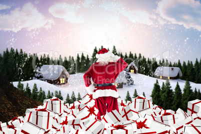 Composite image of santa standing on pile of gifts