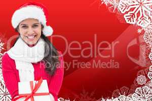 Composite image of festive brunette holding gift