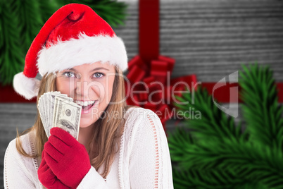 Composite image of festive blonde showing fan of dollars