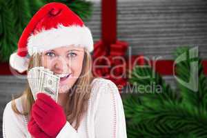 Composite image of festive blonde showing fan of dollars