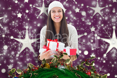 Composite image of festive brunette holding gifts