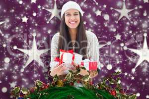 Composite image of festive brunette holding gifts