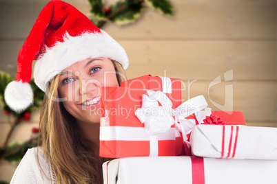 Composite image of festive blonde holding pile of gifts