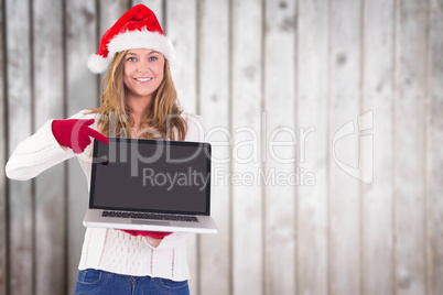 Composite image of festive blonde pointing to laptop