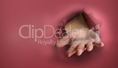 Composite image of hand bursting through paper