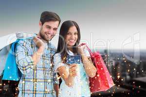 Composite image of couple with shopping bags and credit card