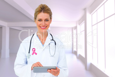 Composite image of blonde doctor using tablet pc Composite image of blonde doctor using tablet pc