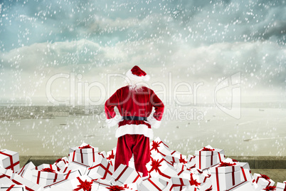 Composite image of santa standing on pile of gifts