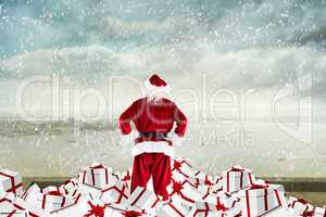 Composite image of santa standing on pile of gifts