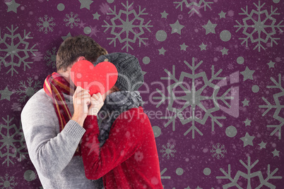 Couple holding a large heart in front of face.