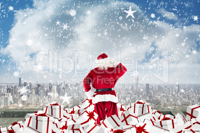 Composite image of santa standing on pile of gifts