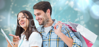 Composite image of happy couple with shopping bags and tablet