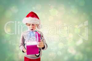 Composite image of festive boy holding a gift