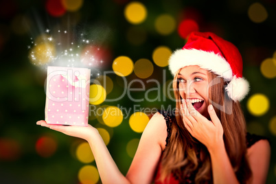 Composite image of festive blonde holding a gift bag