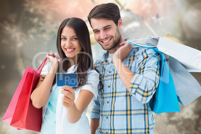 Composite image of couple with shopping bags and credit card