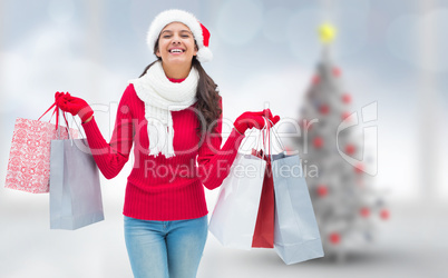 Composite image of festive brunette holding shopping bags