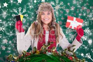 Composite image of happy blonde in winter clothes holding gifts