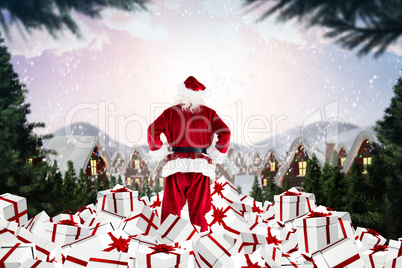 Composite image of santa standing on pile of gifts