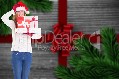 Composite image of festive blonde holding pile of gifts