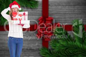 Composite image of festive blonde holding pile of gifts