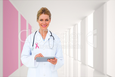 Composite image of blonde doctor using tablet pc