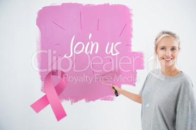 Composite image of happy young woman painting her wall pink