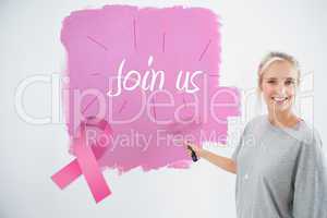 Composite image of happy young woman painting her wall pink