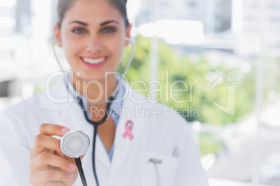 Composite image of pretty young doctor holding up stethoscope