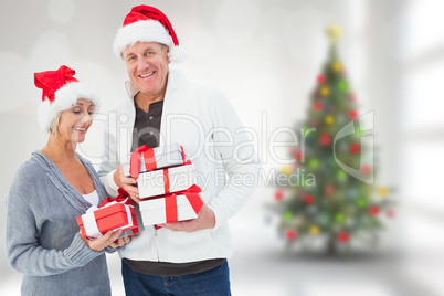 Composite image of festive mature couple holding christmas gifts