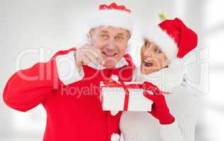 Composite image of festive mature couple holding gift