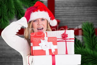 Composite image of festive blonde holding pile of gifts